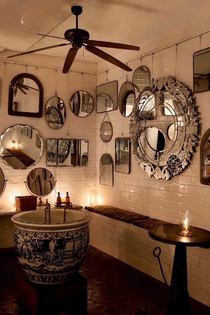 Candle-lit powder room with a porcelain basin and mirrored walls